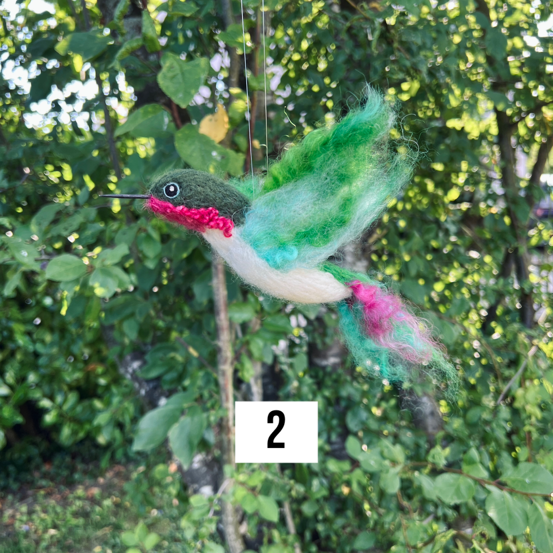 Kolibri aus Filzwolle mit grünen Flügeln und rotem Brustbereich, handgefertigt in der Schweiz