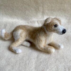 Handgefilzte Hundfigur in hellbraun und weiss, liegend dargestellt